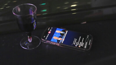 A phone perched on a car plays a simultaneous translation into Spanish as the first general election debate of the 2024 season between U.S. President Joe Biden and his Republican rival, former President Donald Trump, is projected on a giant outdoor screen at the Nite Owl drive-in theater, Thursday, June 27, 2024, in Miami. (AP Photo/Rebecca Blackwell)